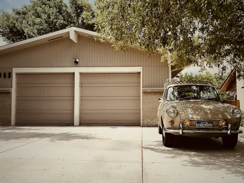 Two-car garage with tan doors and a classic car in the driveway